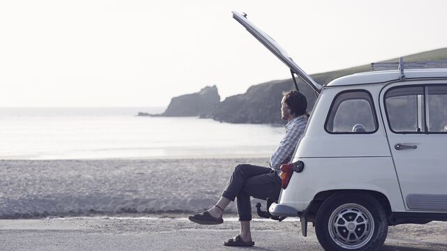 Man sitting in boot of car on beach SMALL